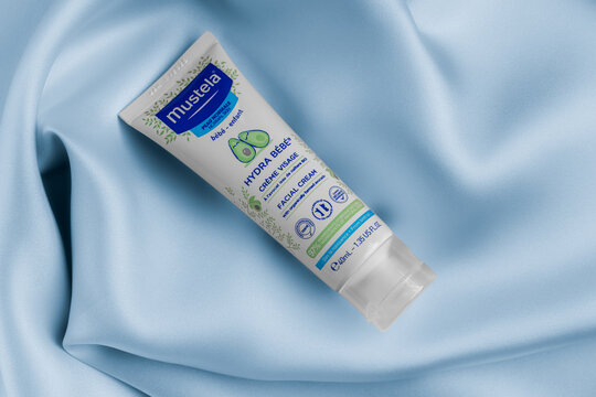 Lviv Ukraine - September 12, 2026: Mustela Hydra Bebe facial cream tube for baby skin care on blue silk fabric background