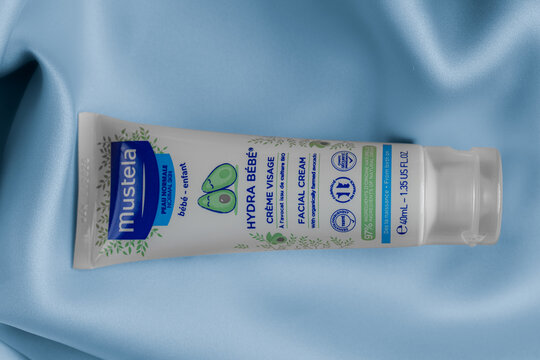 Lviv Ukraine - September 12, 2026: Mustela Hydra Bebe facial cream tube for baby skin care on blue silk fabric background