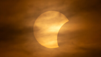 Partial solar eclipse on September 12, 2026, with the Moon visibly covering a significant portion of the Sun. The Sun appears as a bright orange crescent against a dark sky.  © coffeinlix 