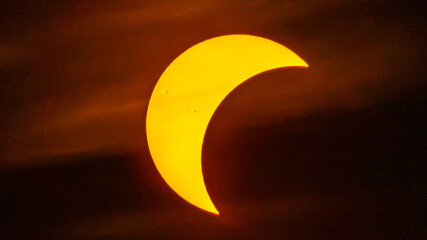 Partial solar eclipse on September 12, 2026, with the Moon visibly covering a significant portion of the Sun. The Sun appears as a bright orange crescent against a dark sky.  © coffeinlix 