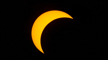 Partial solar eclipse on September 12, 2026, with the Moon visibly covering a significant portion of the Sun. The Sun appears as a bright orange crescent against a dark sky.  © coffeinlix 
