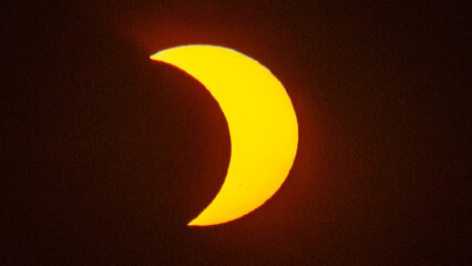 Partial solar eclipse on September 12, 2026, with the Moon visibly covering a significant portion of the Sun. The Sun appears as a bright orange crescent against a dark sky.  © coffeinlix 