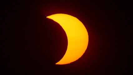 Partial solar eclipse on September 12, 2026, with the Moon visibly covering a significant portion of the Sun. The Sun appears as a bright orange crescent against a dark sky.  © coffeinlix 