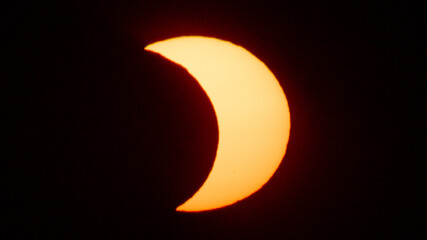 Partial solar eclipse on September 12, 2026, with the Moon visibly covering a significant portion of the Sun. The Sun appears as a bright orange crescent against a dark sky.  © coffeinlix 