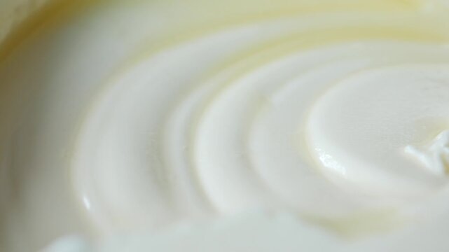 Macro shot of fresh white yogurt in plastic container showing smooth creamy texture and swirls