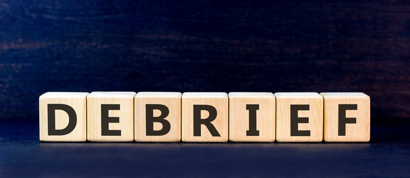 Debrief word symbol. Concept word Debrief on beautiful wooden blocks. Beautiful black table black background. Business debrief word concept. Copy space.