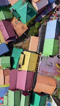 Top-down drone view of colorful rooftops in Jodipan Village, Malang, Indonesia. Brightly painted houses create a vibrant geometric urban pattern in the famous rainbow village.