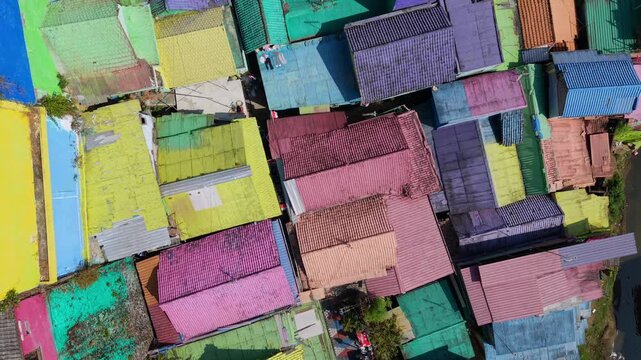 Top-down drone view of colorful rooftops in Jodipan Village, Malang, Indonesia. Brightly painted houses create a vibrant geometric urban pattern in the famous rainbow village.