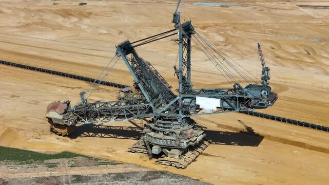 aerial orbit reveals bucket wheel excavator lattice boom framework rusted bucket wheel crawler tracks anchor towering steel machine open pit lignite mine kerpen germany mining equipment drone footage