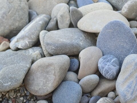 Smooth grey pebbles and stones background texture on a river beach