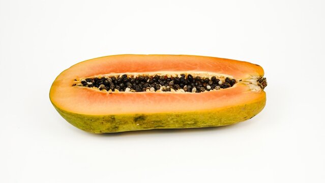 Half cut ripe papaya fruit displaying orange flesh and black seeds inside, isolated on a clean white background.