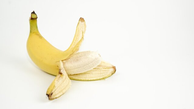 Partially peeled ripe yellow Cavendish banana exposing the inner fruit flesh, isolated on a clean white background.