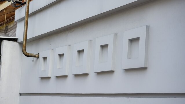 Minimalist white concrete wall texture featuring five repeated square relief panels and subtle shadows.