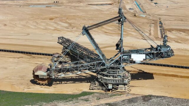 colossal bucket wheel excavator rotates massive cutting wheel terraced lignite pit steel lattice boom cables aerial orbit sand strata hambach coal mine germany heavy machinery brown coal extraction
