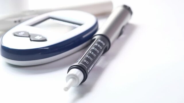 Close-up of diabetes medical equipment including glucose meter and insulin pen