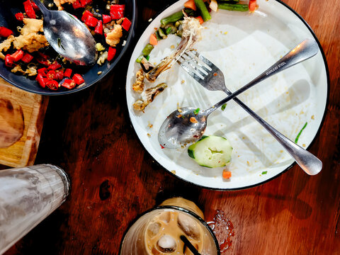 Top view of messy empty plates with food leftovers and iced coffee on a wooden table
