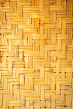 Natural bamboo woven surface with a repeating geometric pattern, interlaced strips, and warm golden brown tones creating a detailed decorative texture.