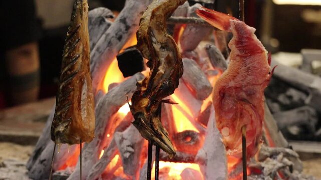 Fish Skewers Standing Upright and Grilling Over Glowing Robata Binchotan Charcoal in Japanese Restaurant 