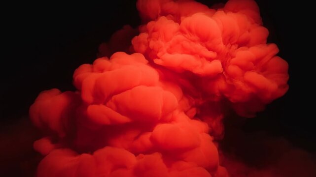 Red mushroom cloud of fiery smoke against black background with glowing lower haze