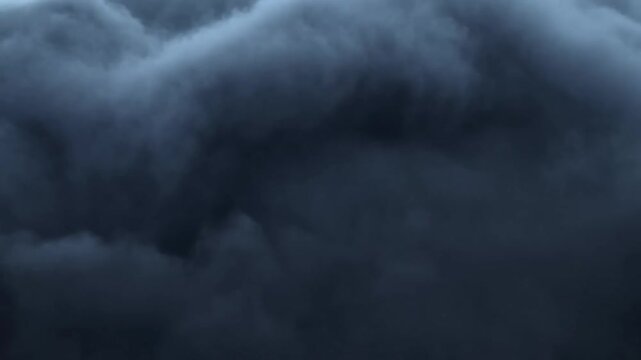 Dark storm clouds move across an overcast sky as dense layers billow and shift