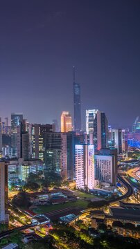 Vertical Time lapse footage of Kuala Lumpur city center at blue hour, featuring modern skyscrapers, illuminated buildings, busy roads, and a vibrant urban skyline in Malaysia.