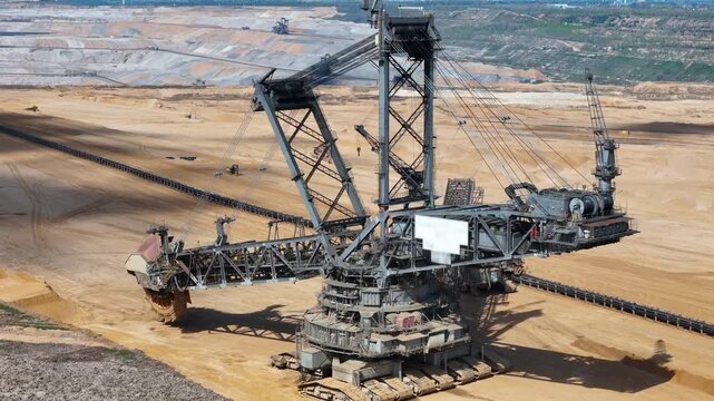 bucket wheel excavator carves terraced levels into hambach open pit mine layered earthen benches step toward conveyor belt network forest edge borders the excavation kerpen germany aerial view