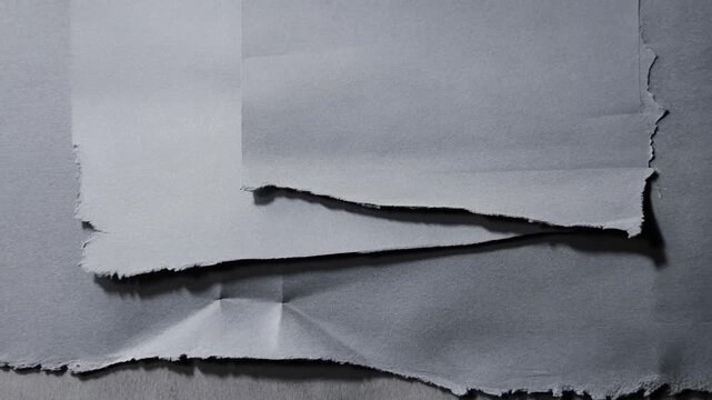 Layers of black torn craft paper with rough ripped edges on dark background