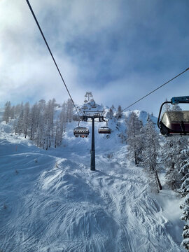 chairlift rising above snowy ski slopes and frosted trees