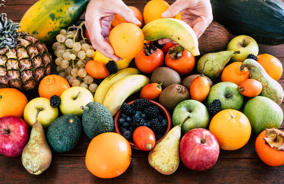 Two human hands with different kind of fresh fruits in orange, yellow and green colors. Healthy eating concept and detox diet. Vegan and vegetarian food.