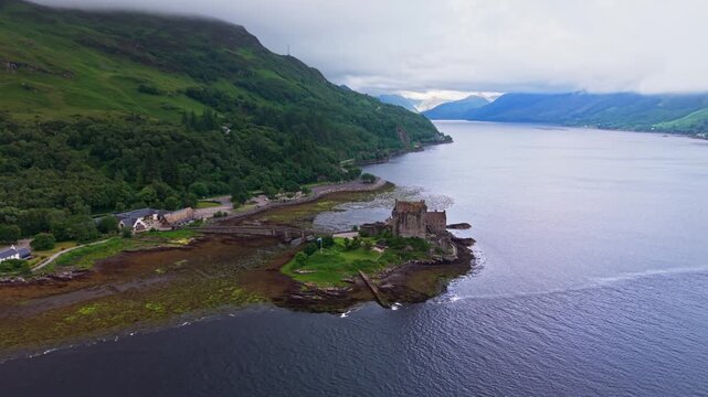 Aerial flight around Eilean Donan Castle on its tidal island where Loch Duich, Loch Long and Loch Alsh meet in the misty Scottish Highlands, United Kingdom. 4K UHD video.