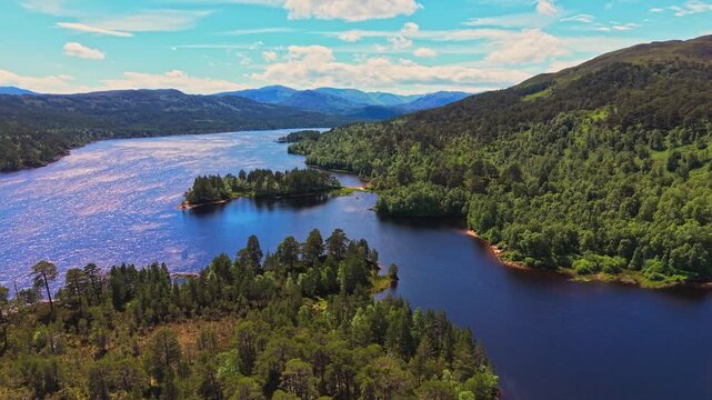 Aerial drone view over Loch Beinn Mheadhoin in Glen Affric, Scotland, with forested islands, wooded hills and blue Highland water. 4K UHD video.