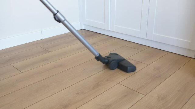 A close up view of a vacuum cleaner on wood floor cleaning dust and dirt in a home or office room