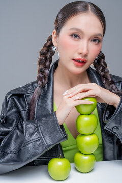 Trendy stylish woman balancing green apple on head, showcasing playful attitude, fashion beauty, quirky balance, youthful confidence, creative diet concept, modern wellness, and edgy cool lifestyle.