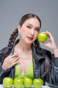 Trendy stylish woman balancing green apple on head, showcasing playful attitude, fashion beauty, quirky balance, youthful confidence, creative diet concept, modern wellness, and edgy cool lifestyle.