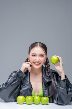 Trendy stylish woman balancing green apple on head, showcasing playful attitude, fashion beauty, quirky balance, youthful confidence, creative diet concept, modern wellness, and edgy cool lifestyle.