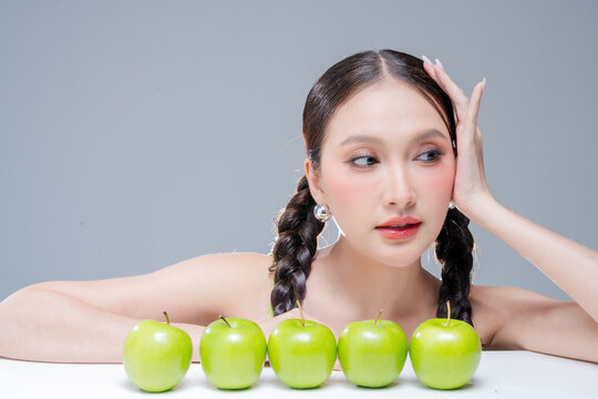 Radiant cheerful woman holding fresh green apple, expressing healthy lifestyle, organic diet vitality, dental beauty, wellness balance, joyful nutrition, natural freshness, and vibrant body detox.