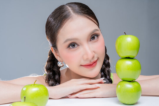Radiant cheerful woman holding fresh green apple, expressing healthy lifestyle, organic diet vitality, dental beauty, wellness balance, joyful nutrition, natural freshness, and vibrant body detox.