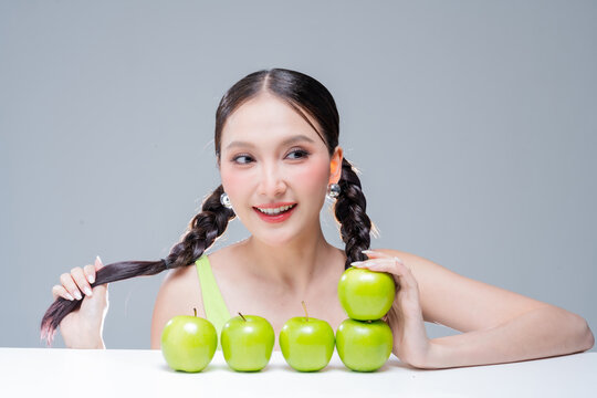 Radiant cheerful woman holding fresh green apple, expressing healthy lifestyle, organic diet vitality, dental beauty, wellness balance, joyful nutrition, natural freshness, and vibrant body detox.