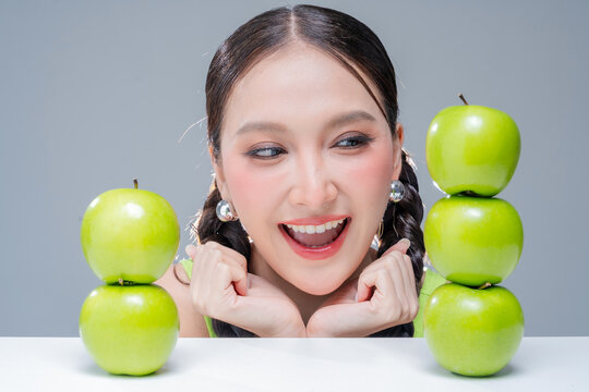 Radiant cheerful woman holding fresh green apple, expressing healthy lifestyle, organic diet vitality, dental beauty, wellness balance, joyful nutrition, natural freshness, and vibrant body detox.