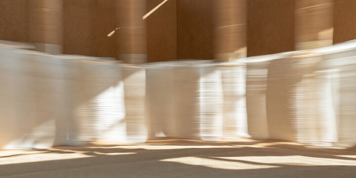 Three grain sacks in an abstract blur with warm golden light inside a rustic barn, featuring a chestnut brown wall for copy space