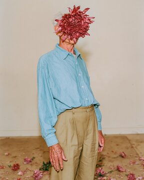 Surreal portrait of an older person with a russet chrysanthemum instead of a head, wearing a soft blue shirt for creative art and wellness