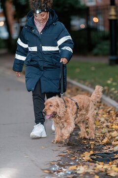 Middle Eastern woman walking her dog in the dark, wearing a headlamp and reflective tape for road safety and visibility