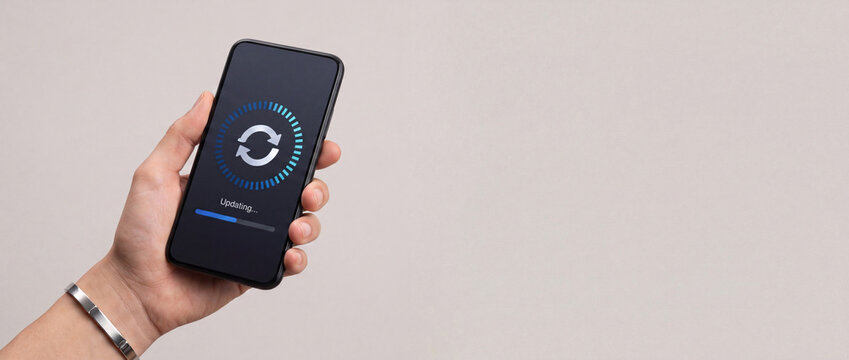 Person holding generic smartphone displaying software update progress bar and sync icon on neutral background for technology concept.