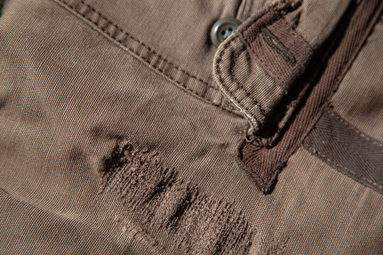 Close-up of distressed brown vintage fabric with zipper and frayed edges. Heavily worn authentic textile showing natural aging, scratches and soft material texture.

