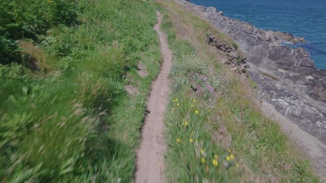 POV walking along the Southwest coast path at Pentire, Newquay, Cornwall, England on a hot sunny June day.