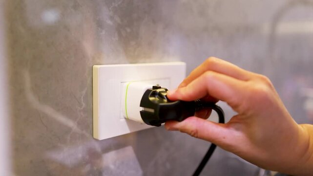 Hand plugging electrical adapter into wall socket for international travel convenience.