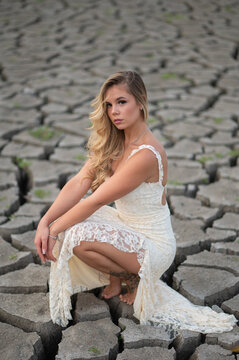 Woman crouching on cracked earth representing drought and climate change