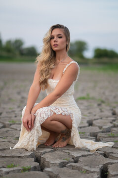Woman crouching on dry cracked earth with tattoo