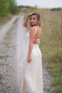 Blonde woman posing in lace dress on rural path