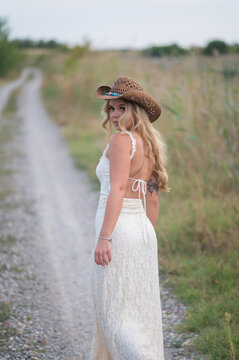 Blonde woman wearing cowboy hat walking country path